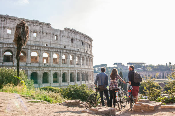 Three happy young friends tourists with bikes at Colosseum in Rome having fun Three happy young friends tourists with bikes at Colosseum in Rome having fun bike touring stock pictures, royalty-free photos & images